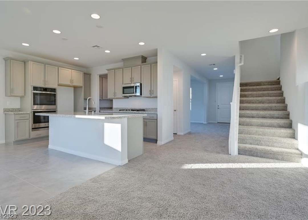 Open kitchen with an island, double ovens, and a staircase inside the home at 1509 Carlsbad St in Boulder City