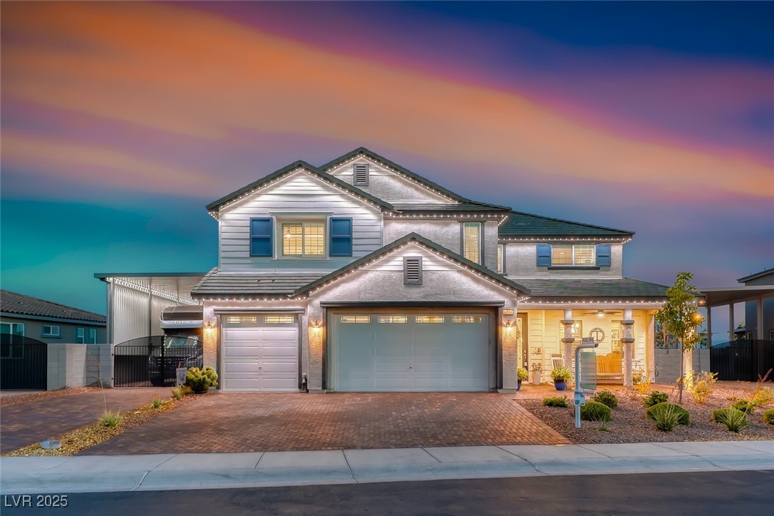 Two-story home lit at dusk with a paver driveway and covered front porch at 1523 Great Sands St in Boulder City