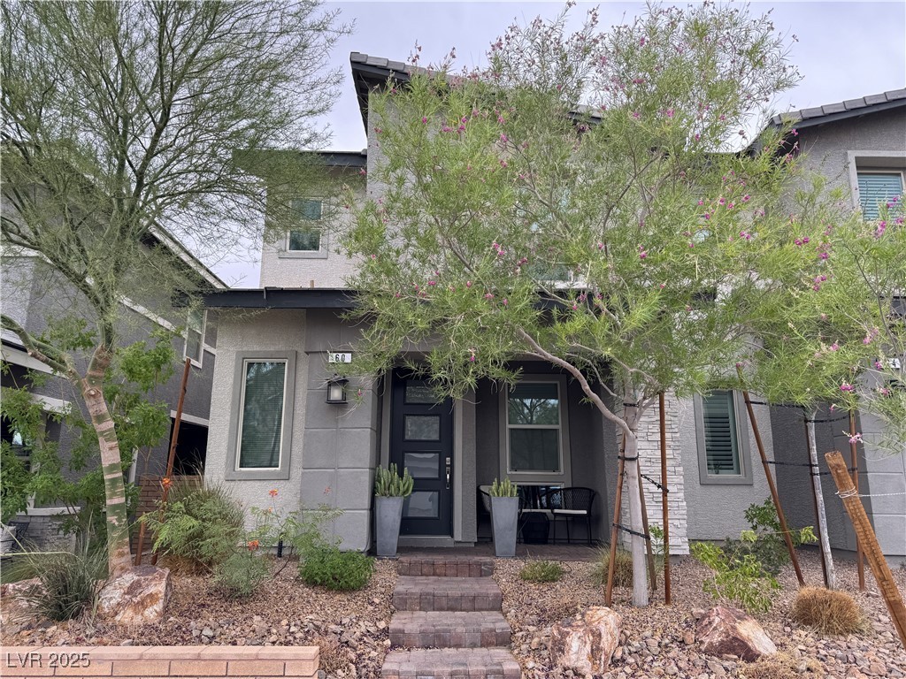 Front entry of a modern two-story home shaded by desert willow trees at 60 Alla Breve Ave in Henderson